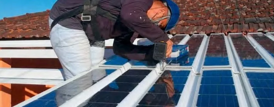 A technician installing a lightweight solar roof panel on a tiled roof.
